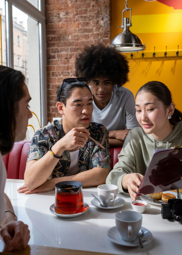 Several people gathered around a table at a cafe discussing notes.